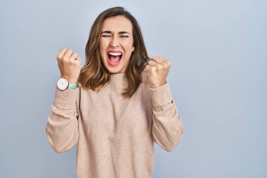 Young woman standing over isolated background excited for success with arms raised and eyes closed celebrating victory smiling. winner concept. 