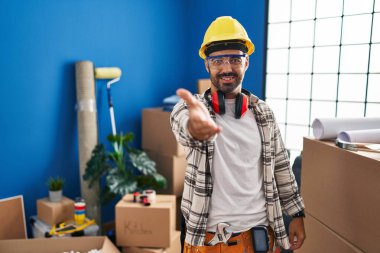 Evde çalışan, sakallı, neşeli gülümseyen, yardım eli uzatan ve kabul gören genç İspanyol bir adam.. 