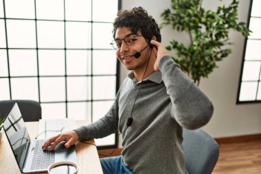Ofiste çalışırken gülümseyen İspanyol bir çağrı merkezi ajanı..