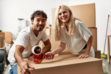 Genç ve güzel bir çift gülümsüyor. Yeni evlerinde karton kutular paketliyorlar..