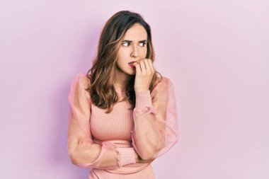 Günlük kıyafetler giyen genç İspanyol kız gergin ve gergin görünüyor. Ağzı tırnak yiyen ellerle. anksiyete. 