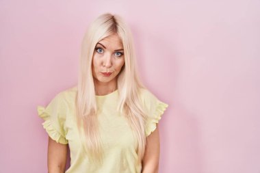 Caucasian woman standing over pink background skeptic and nervous, frowning upset because of problem. negative person. 