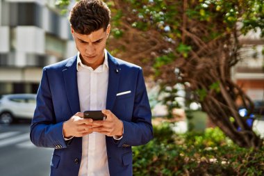 Genç adam parkta akıllı telefon kullanıyor.