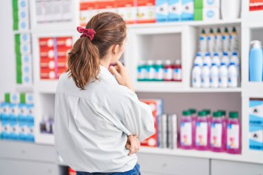 Young woman customer standing on back view at pharmacy