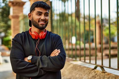 Sokakta kulaklık takmış, kendinden emin gülümseyen genç bir Arap.