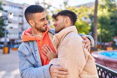 İki erkek parkta birbirlerine sarılıyorlar.