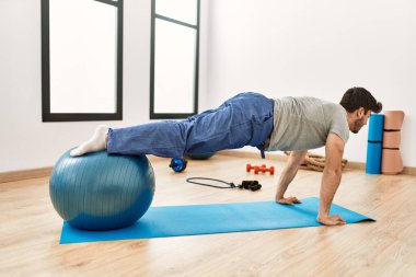 Genç İspanyol sporcu mutlu bir şekilde gülümsüyor. Spor merkezinde formda top kullanıyor..