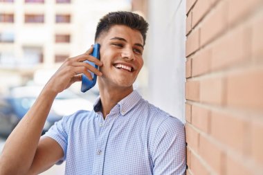Genç İspanyol adam gülümsüyor. Kendine güveniyor. Sokakta akıllı telefondan konuşuyor.