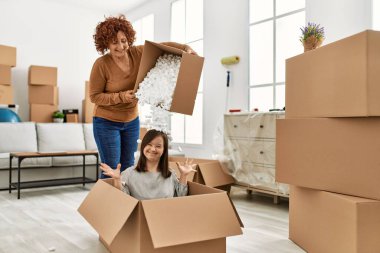 Olgun anne ve Down sendromlu kız yeni bir eve taşınıyor, karton köpükle eğleniyor.