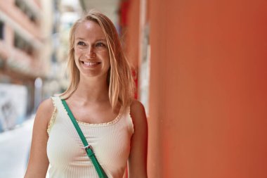 Young blonde woman smiling confident looking to the side at street