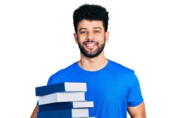 Sakallı genç Arap adam elinde bir yığın kitap tutuyor. Olumlu ve mutlu görünüyor. Kendine güvenen bir gülümsemeyle dişlerini gösteriyor. 