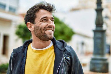 Yakışıklı, sakallı, açık havada mutlu gülümseyen bir İspanyol.