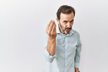Middle age hispanic man with beard standing over isolated background doing italian gesture with hand and fingers confident expression 