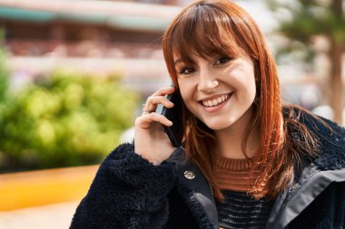 Parktaki akıllı telefondan konuşan, kendine güvenen genç bir kadın.