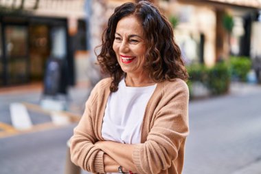 Middle age hispanic woman smiling happy with crossed arms outdoors