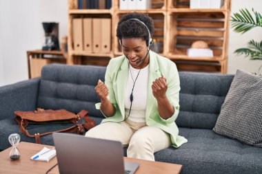 African american woman doing online session at consultation office screaming proud, celebrating victory and success very excited with raised arms 