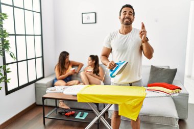 Evde giysilerini ütüleyen, umut ve gözlerin kapalı gülümseyerek el hareketi yapan genç bir İspanyol. Şans ve batıl inançlar. 