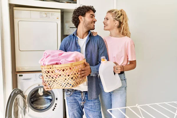 Jovem Casal Sorrindo Feliz Segurando Cesta Roupa Garrafa Detergente Casa — Fotografia de Stock