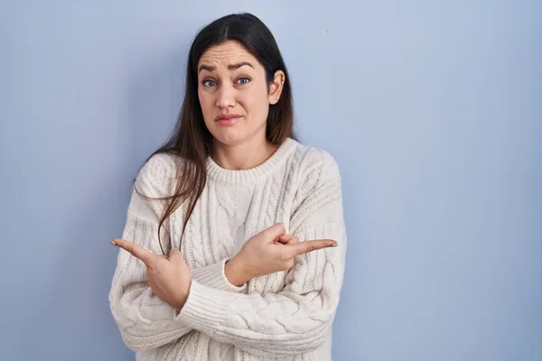 Young Brunette Woman Standing Blue Background Pointing Both Sides Fingers — стоковое фото