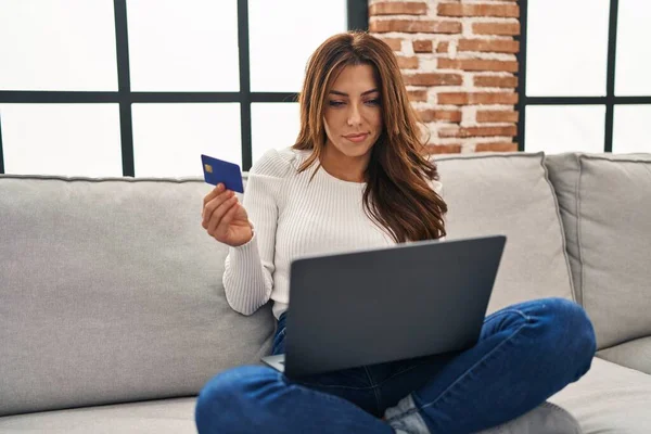 年轻的惊慌失措的女人坐在家里沙发上 用笔记本电脑和信用卡 — 图库照片