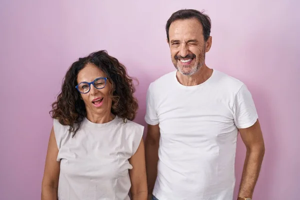 Middle Age Hispanic Couple Together Pink Background Winking Looking Camera —  Fotos de Stock