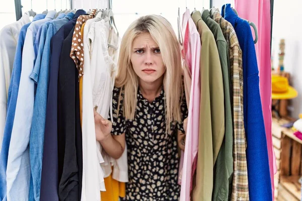 Young Blonde Woman Searching Clothes Clothing Rack Skeptic Nervous Frowning — Stockfoto