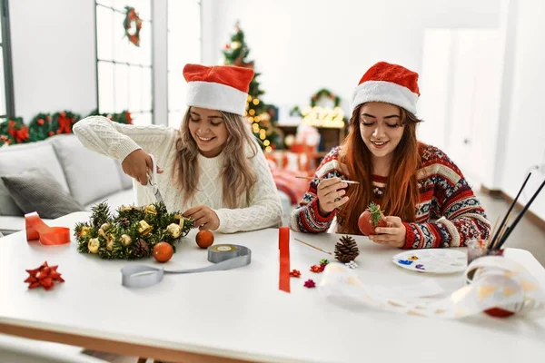 家庭でテーブルの上に座って手作りのクリスマスの装飾を作る女性カップル — ストック写真