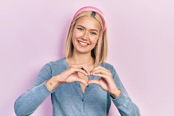 Beautiful Blonde Woman Standing Pink Background Smiling Love Doing Heart — 스톡 사진