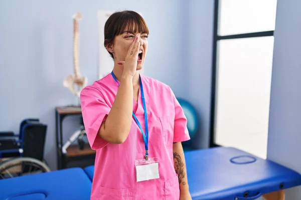 リハビリテーションクリニックで働く若いブルネットの女性は大声で叫び 口の中で手で横に大声で叫んでいます コミュニケーションの概念 — ストック写真