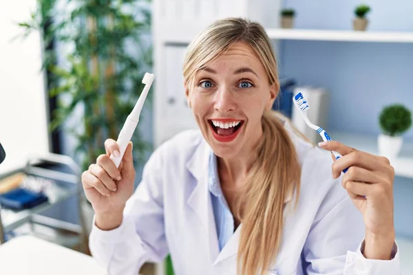 Beautiful Dentist Woman Holding Ordinary Toothbrush Electric Toothbrush Smiling Laughing — Zdjęcie stockowe