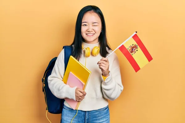 Young Chinese Girl Exchange Student Holding Spanish Flag Winking Looking —  Fotos de Stock