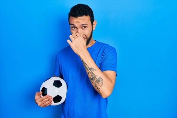 Hispanic Man Beard Holding Soccer Ball Smelling Something Stinky Disgusting — ストック写真