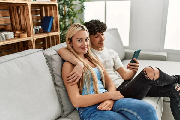 年轻夫妇用智能手机坐在家里的沙发上 — 图库照片