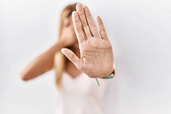 Blonde beautiful young woman standing over white isolated background covering eyes with hands and doing stop gesture with sad and fear expression. embarrassed and negative concept.
