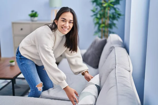 年轻的惊慌失措的女人在家里整理沙发 — 图库照片