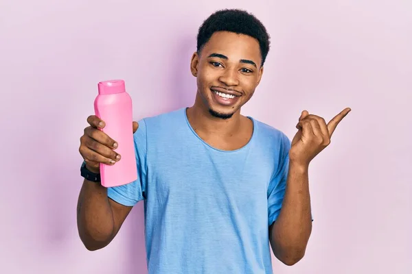 Jonge Afro Amerikaanse Man Met Shampoo Fles Glimlachen Gelukkig Wijzend — Stockfoto