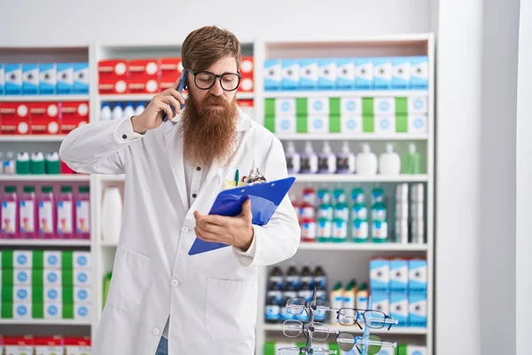 Young Redhead Man Pharmacist Talking Smartphone Reading Document Pharmacy — Fotografia de Stock