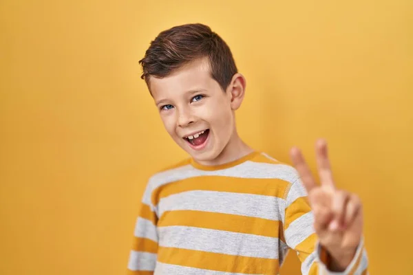 Niño Caucásico Joven Pie Sobre Fondo Amarillo Sonriendo Mirando Cámara — Foto de Stock