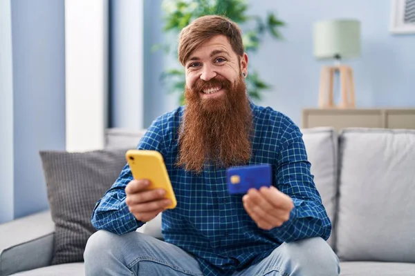 Young Redhead Man Using Smartphone Credit Card Sitting Sofa Home — 스톡 사진