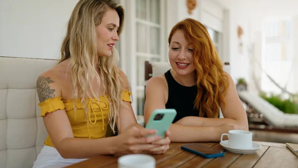 Dvě Ženy Pomocí Smartphonu Pití Kávy Sedí Stole Doma Terase — Stock fotografie