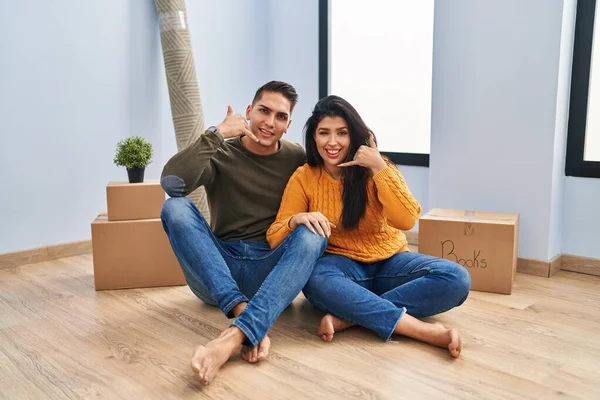 Young Couple Sitting Floor New Home Smiling Doing Phone Gesture — Stock Photo, Image