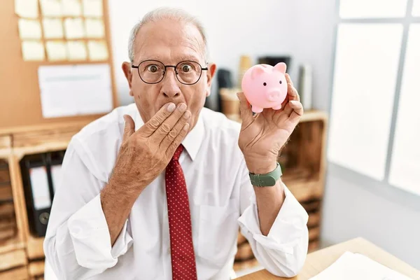 Senior Business Man Holding Piggy Bank Covering Mouth Hand Shocked — Stok fotoğraf