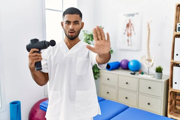 Young Indian Physiotherapist Holding Therapy Massage Gun Wellness Center Doing — Stockfoto