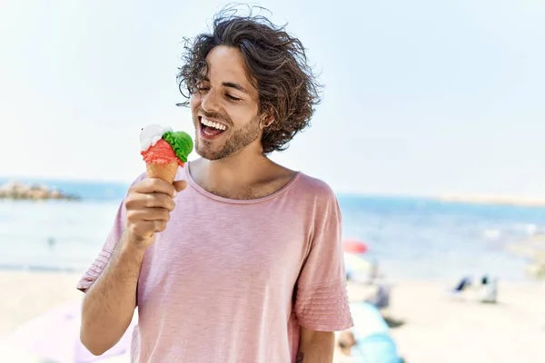 年轻的惊慌失措的男人在海滩上高兴地吃着冰激凌 — 图库照片