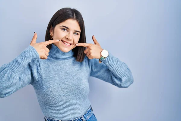 Mavi Arka Planda Dikilen Genç Spanyol Kadın Gülümsüyor Parmaklarıyla Ağzıyla — Stok fotoğraf