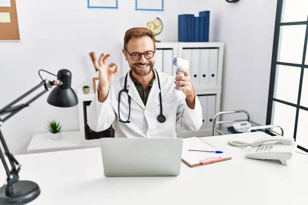 Middle Age Doctor Man Holding Thermometer Clinic Doing Sign Fingers — Stock Photo, Image