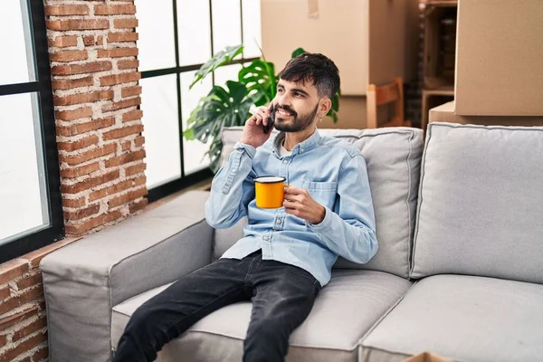 Young Hispanic Man Talking Smartphone Drinking Coffee New Home —  Fotos de Stock