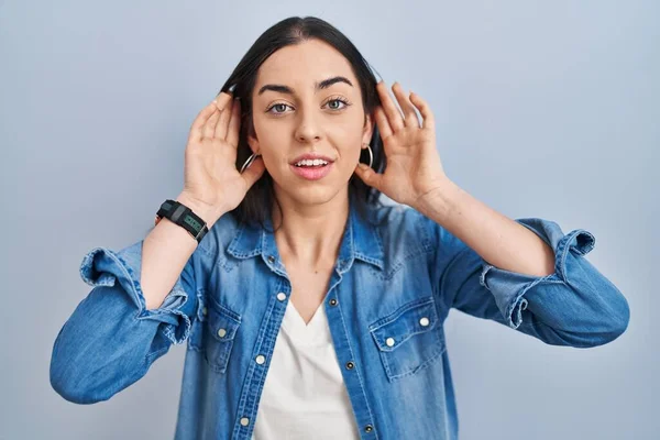 Hispanic Woman Standing Blue Background Trying Hear Both Hands Ear — стоковое фото