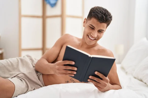 Young Hispanic Man Reading Book Lying Bed Bedroom — Fotografia de Stock