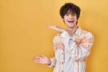 Gündelik yaz gömleği giyen, elleri büyük ve büyük boy işareti gösteren, ölçü sembolü olan genç bir adam. Kameraya bakıp gülümsüyor. ölçüm kavramı. 